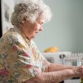 woman in yellow and green floral shirt holding white ceramic mug